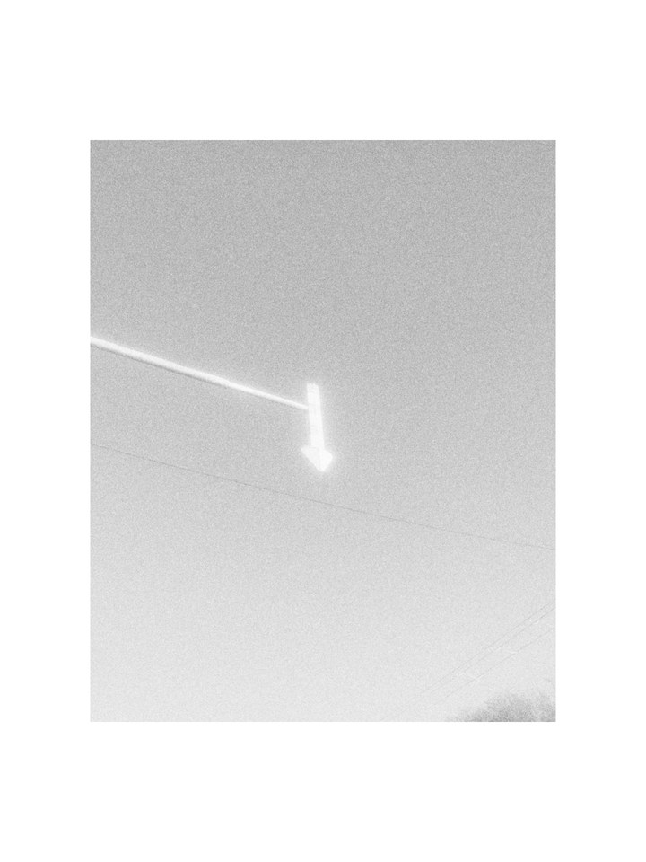 An arrow sign glowing against the sky