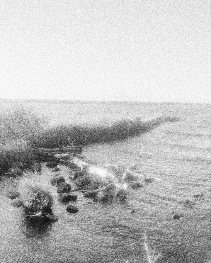 Stones along a lake shore, the water glowing in the sun